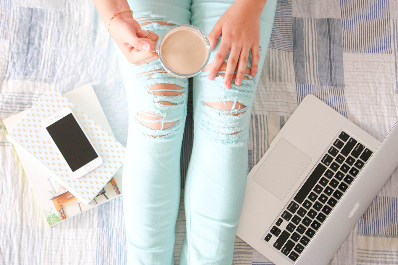 Women in jeans with coffee, laptop and phone